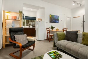 A modern living room with a sofa, a chair, a dining table, and a kitchen in the background. - Cozy Old North Stay • Steps from Yarkon Park (Tel Aviv)