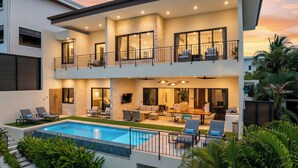 A modern two-story house with a swimming pool, outdoor seating, and a balcony.