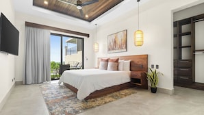 A modern bedroom with a large bed, a ceiling fan, a TV, and a sliding glass door to the balcony.