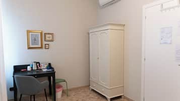 Une petite pièce comprenant un bureau, une chaise, une armoire et une poubelle.