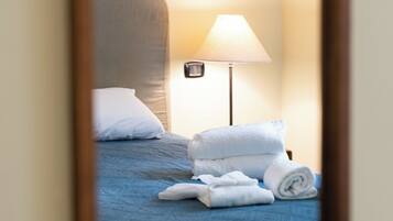 Une chambre d’hôtel avec un lit, une lampe et des serviettes.
