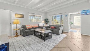 A spacious living room with two grey sofas, a coffee table, a patterned rug, and a lamp.