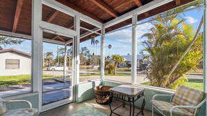 A covered patio with a view of palm trees and a street.