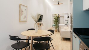 A modern kitchen with a black countertop, a ceiling fan, and a dining area with a round table and four chairs.