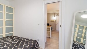 Quarto com cama, guarda-roupa e secretária com cadeira.