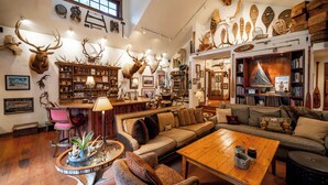 A spacious living room with a wooden coffee table, a sofa, and a bookshelf filled with books and decorative items. - THE FOX HOUSE on Flathead Lake: Lakefront Luxury Living (Bigfork)