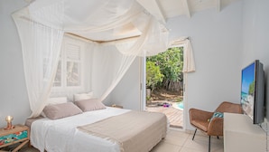 Ein Schlafzimmer mit Bett, Nachttisch, Fernseher und Blick ins Freie.