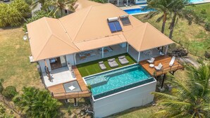 A two-story house with a swimming pool, a covered patio, and a view of a neighboring pool. - Luna Moona (Le Vauclin)