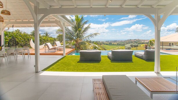 A modern outdoor lounge area with a pool, seating, and a view of the landscape. - Luna Moona (Le Vauclin)