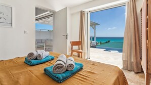 Une chambre avec un lit, des serviettes, une chaise et une vue sur l’océan.