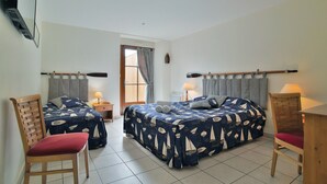 Un dormitorio con dos camas, una silla de madera, una mesita de noche y una lámpara.