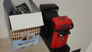 A coffee machine and a box of coffee pods on a wooden table. - Bnb Massaua (Torino)