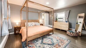 A bedroom with a four-poster bed, a dresser, a mirror, and a patterned rug. - Relax & Recharge – Spacious Wheatridge Stay w/ Backyard Fun (Wheat Ridge)