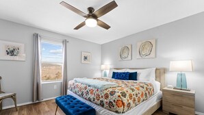 A bedroom with a bed, a blue bench, a nightstand with a lamp, and a ceiling fan. - Casa Bonita Azul | 3 bedroom | 2 bath | Sleeps 8 (Branson)