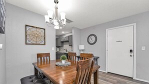 A dining area with a wooden table, six chairs, a chandelier, a clock, and a 'No Smoking' sign on the door. - Casa Bonita Azul | 3 bedroom | 2 bath | Sleeps 8 (Branson)