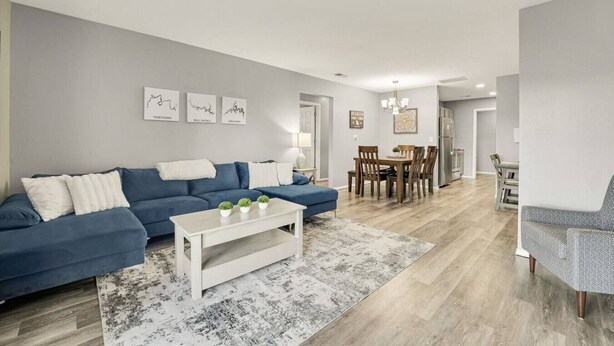 A modern living room with a blue sofa, a white coffee table, and a dining area with wooden chairs and a table. - Casa Bonita Azul | 3 bedroom | 2 bath | Sleeps 8 (Branson)