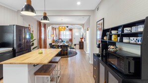 A modern kitchen with wooden countertops, a dining area with a round table, and a black microwave on the counter.