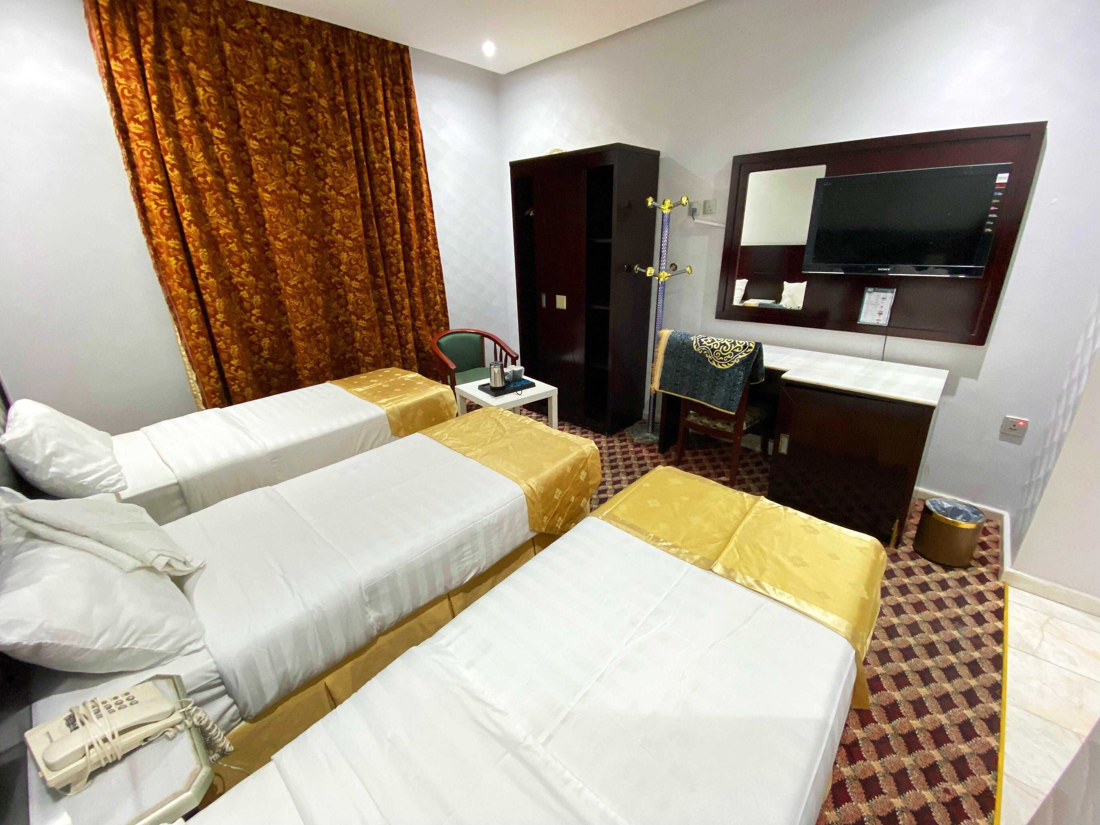 A hotel room with two beds, a desk, a chair, a mirror, and a telephone.