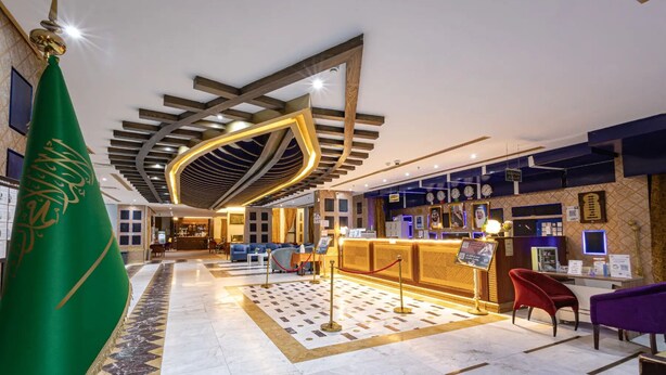 A hotel lobby with a reception desk, seating area, and a flag. - alroh alhora hotel (Makkah)