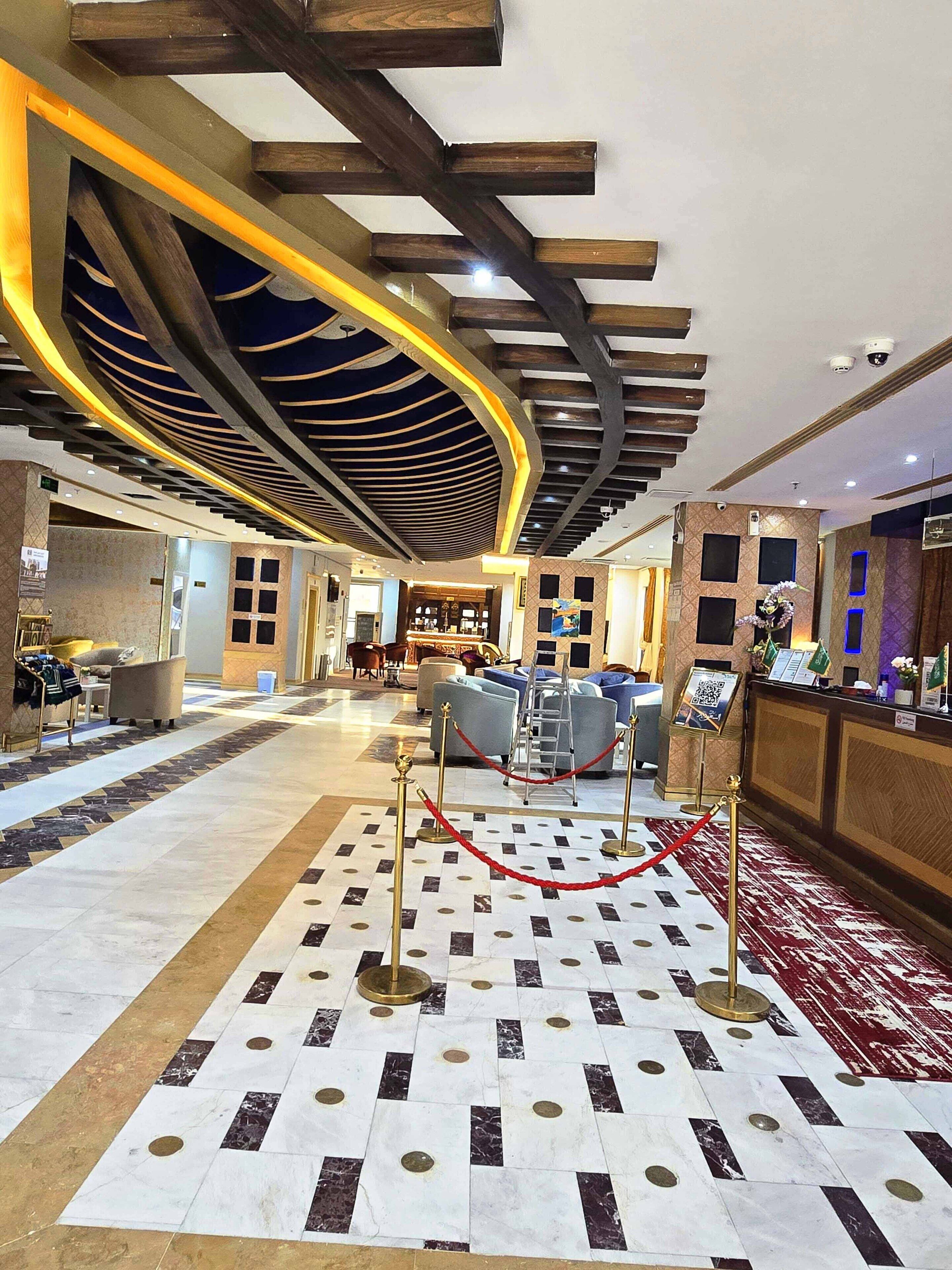 Eine Hotelhalle mit Empfangstresen, Sitzgelegenheiten und einem gemusterten Boden.