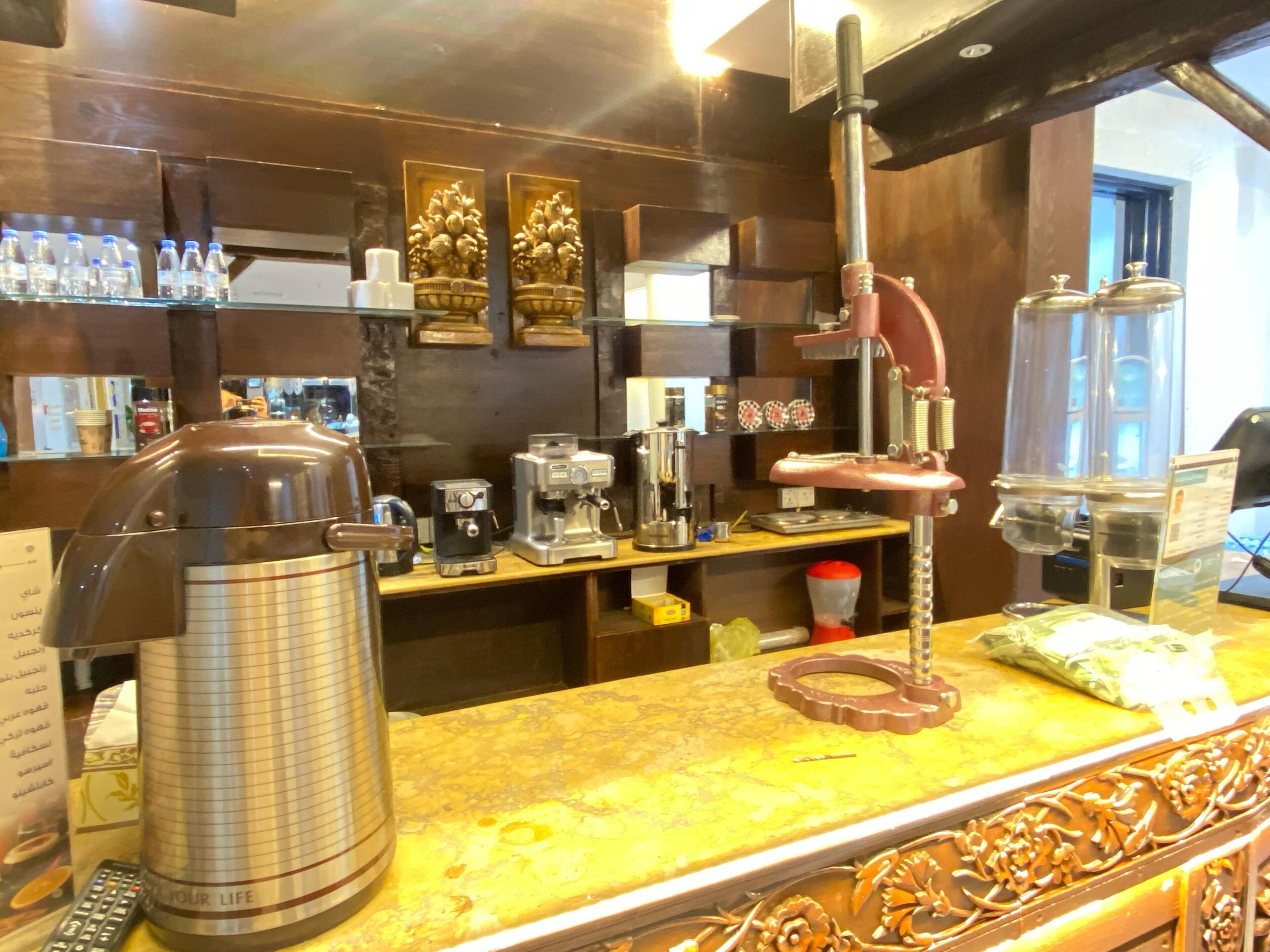 Una zona de bar con máquinas de café, una prensa francesa y un dispensador de agua.
