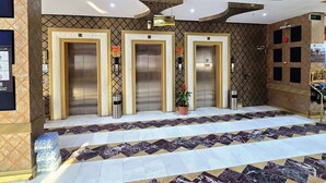 A hotel lobby with three elevators, a reception desk, and a patterned floor. - alroh alhora hotel (Makkah)
