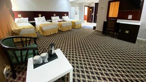 A hotel room with two beds, a small table with a kettle, and a chair. - alroh alhora hotel (Makkah)