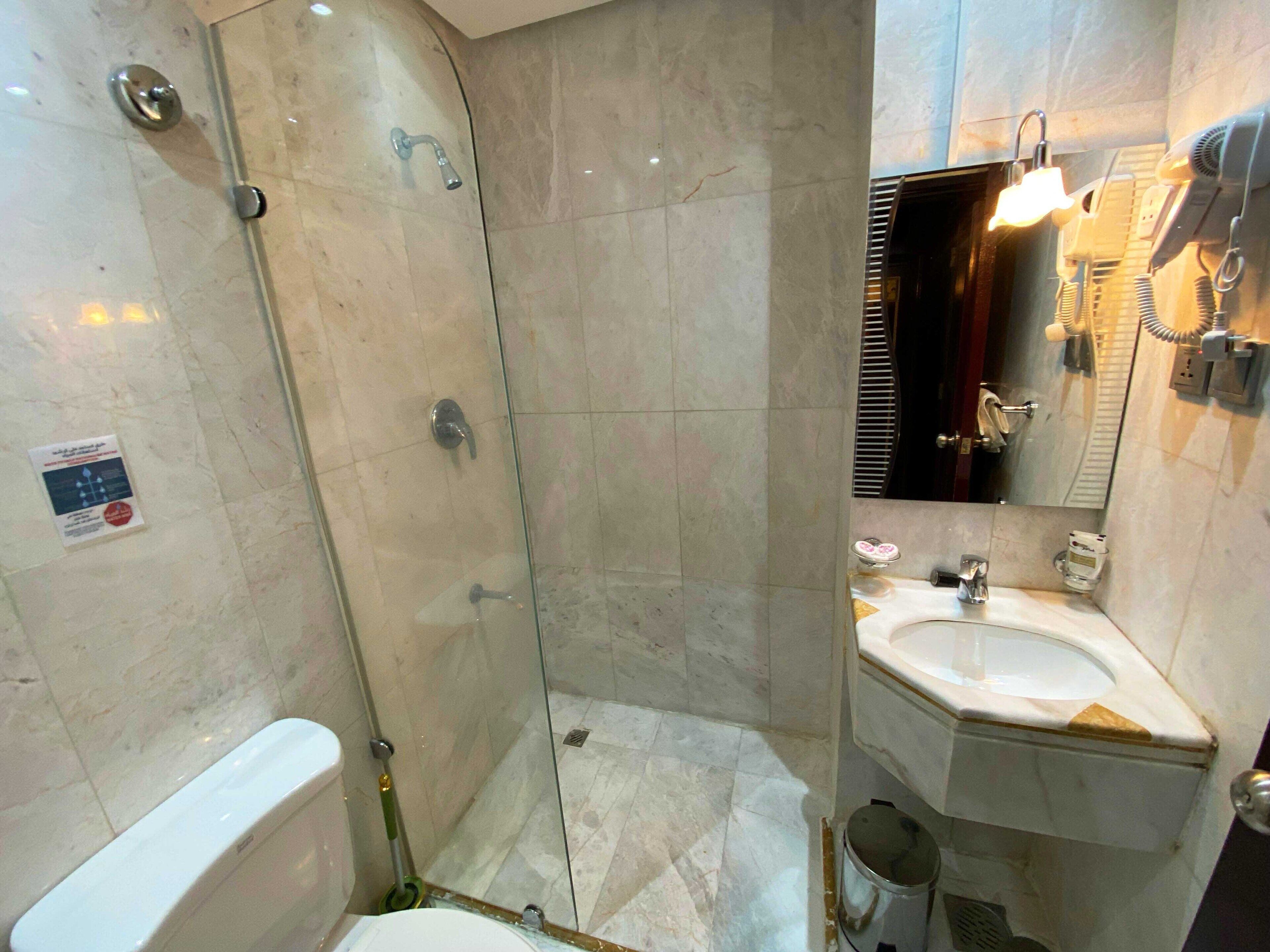A bathroom with a glass-enclosed shower, a sink, and a toilet.