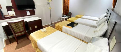 A hotel room with two single beds, a desk with a chair, a TV, a telephone, and a trash bin.