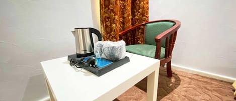 A small white table with a kettle, a power strip, and a bubble wrap package.