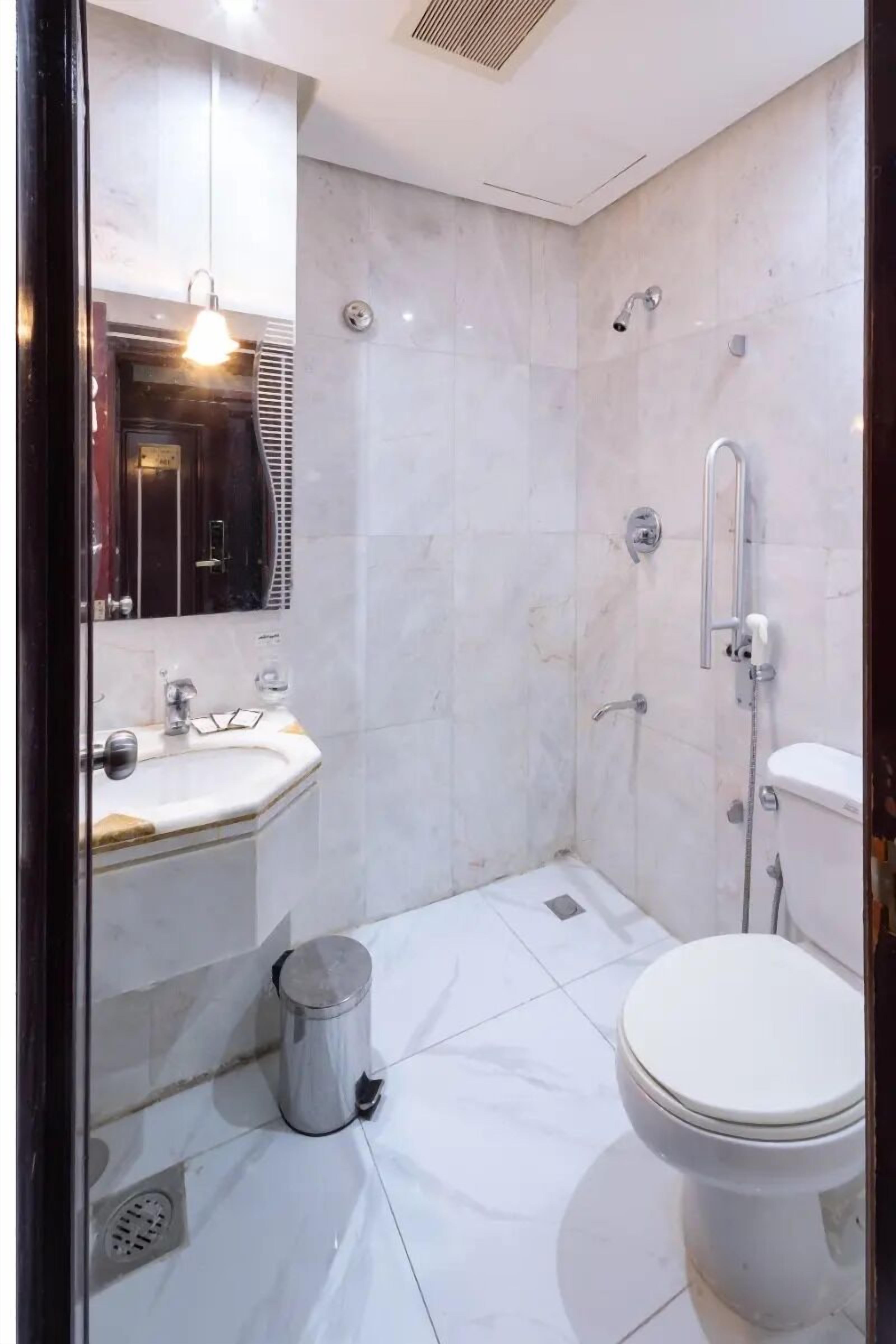 Een badkamer met een witte wastafel, spiegel, toilet en douche.