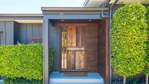 A modern house with a wooden front door, a small porch, and a sign that reads "Home".