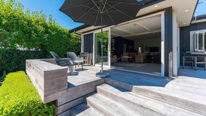 A modern house with a patio area, outdoor seating, and a large umbrella.