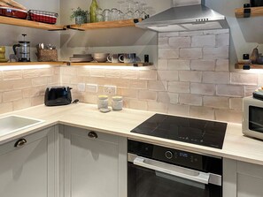 A modern kitchen with a built-in dishwasher, a stovetop, and a brick backsplash. - 2 bedroom accommodation in Kielder (Kielder)
