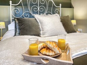 A neatly made bed with a tray of croissants and orange juice, a fluffy white pillow, and a decorative metal headboard. - 2 bedroom accommodation in Kielder (Kielder)