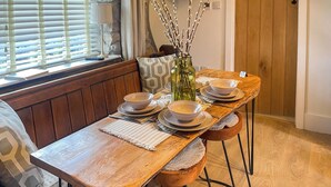 A wooden dining table with a placemat, set with bowls and plates, in a room with wooden flooring and a bench. - 2 bedroom accommodation in Kielder (Kielder)