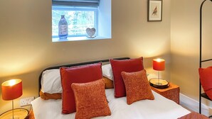 A neatly made bed with red and white bedding, two bedside lamps, a window with a view, and a framed picture on the wall. - 2 bedroom accommodation in Kielder (Kielder)