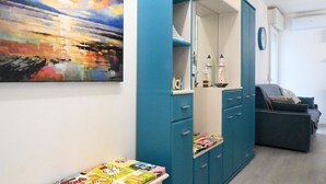 Une pièce avec un meuble bleu, un canapé et un tableau abstrait aux couleurs vives accroché au mur.