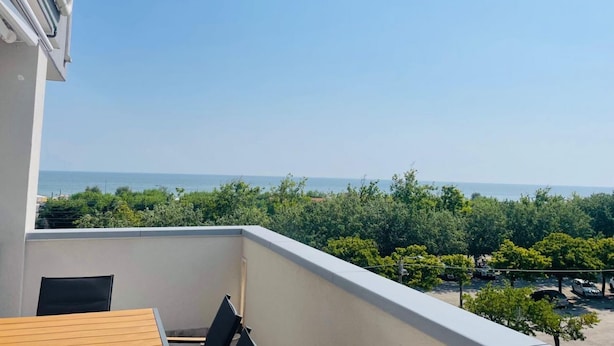 Un balcon avec vue sur la mer et la verdure.
