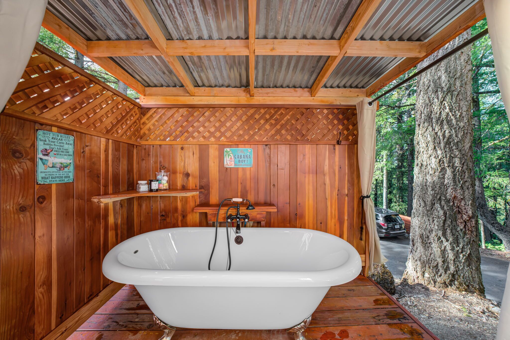 A wooden cabin with a large bathtub, wooden walls, and a view of the forest.