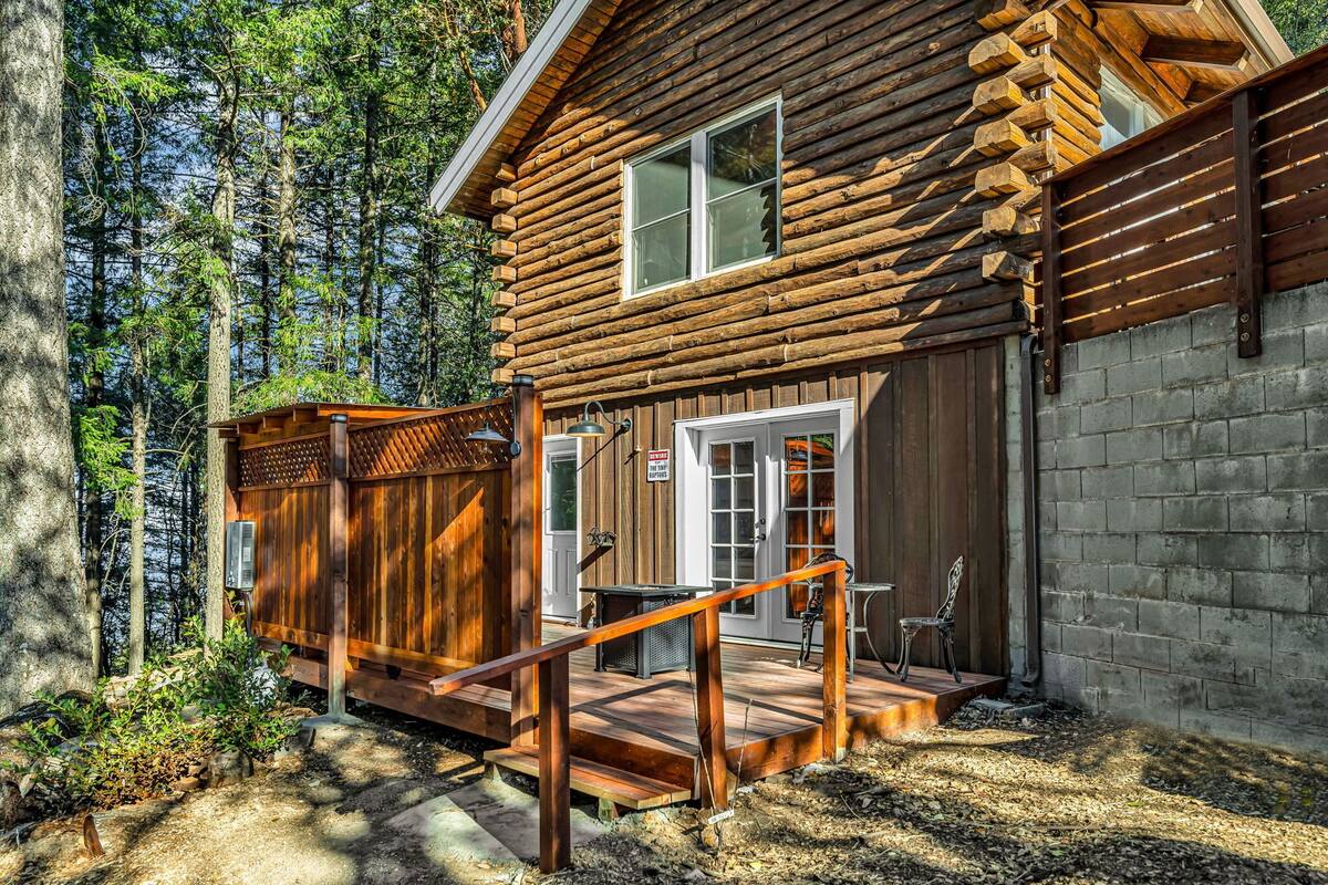 Une cabane en rondins avec une terrasse en bois, un porche couvert et un mur en briques.