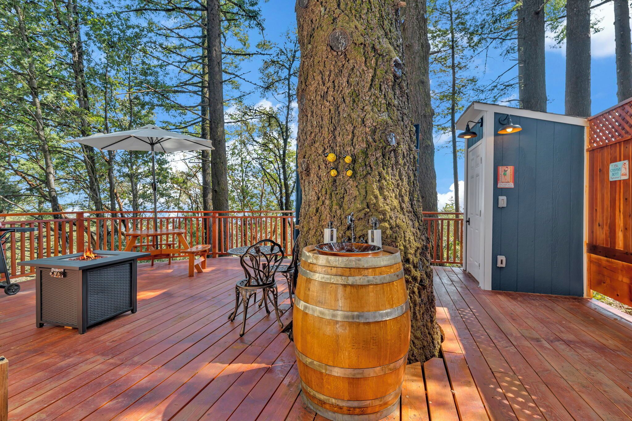 A wooden deck with a fire pit table, outdoor seating, and a barrel.