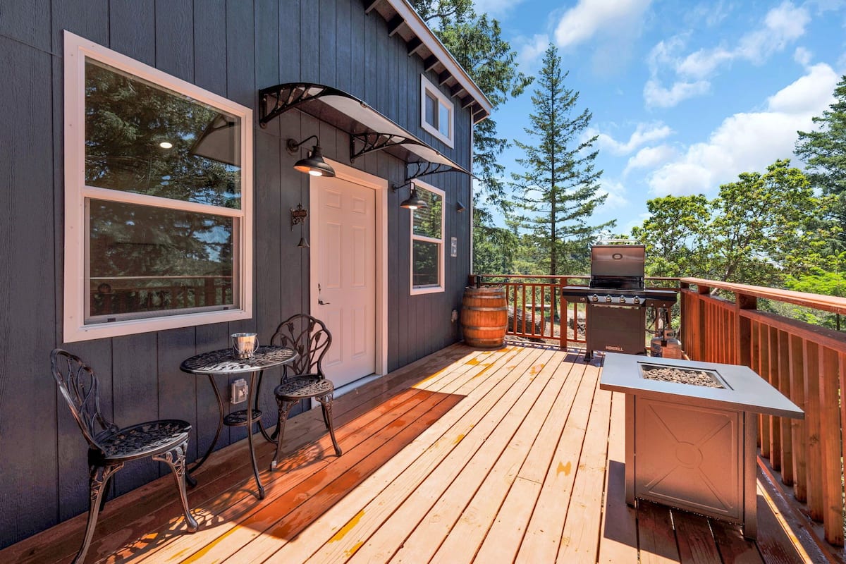 Une terrasse avec un barbecue, des sièges d’extérieur et une vue sur les arbres.