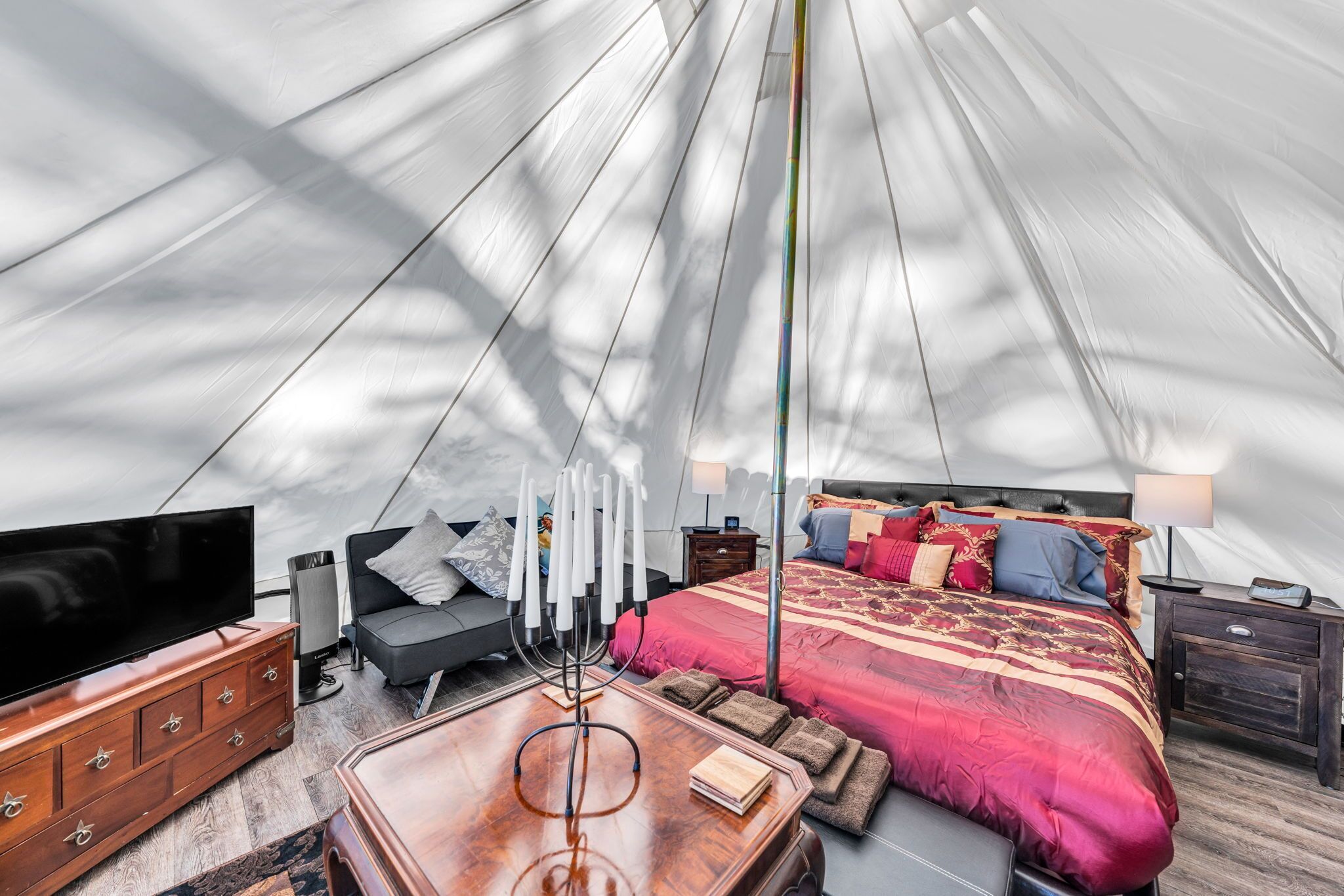 Ein Zeltraum mit Bett, Nachttischen, Fernseher und Massagesessel.