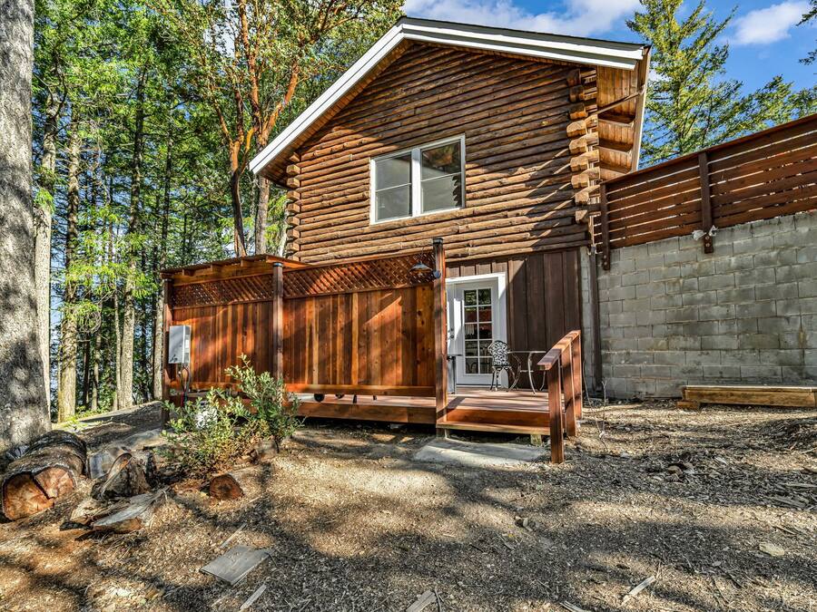Une cabane en rondins avec un porche, une porte et une fenêtre.