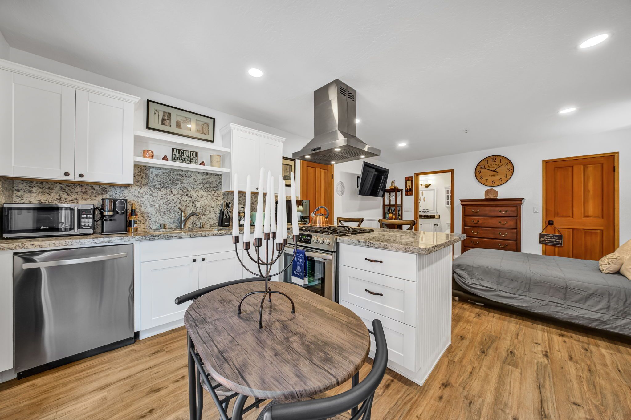 A compact kitchen with white cabinets, a built-in microwave, and a gas stove. There is a dining table with chairs and a decorative candelabra.