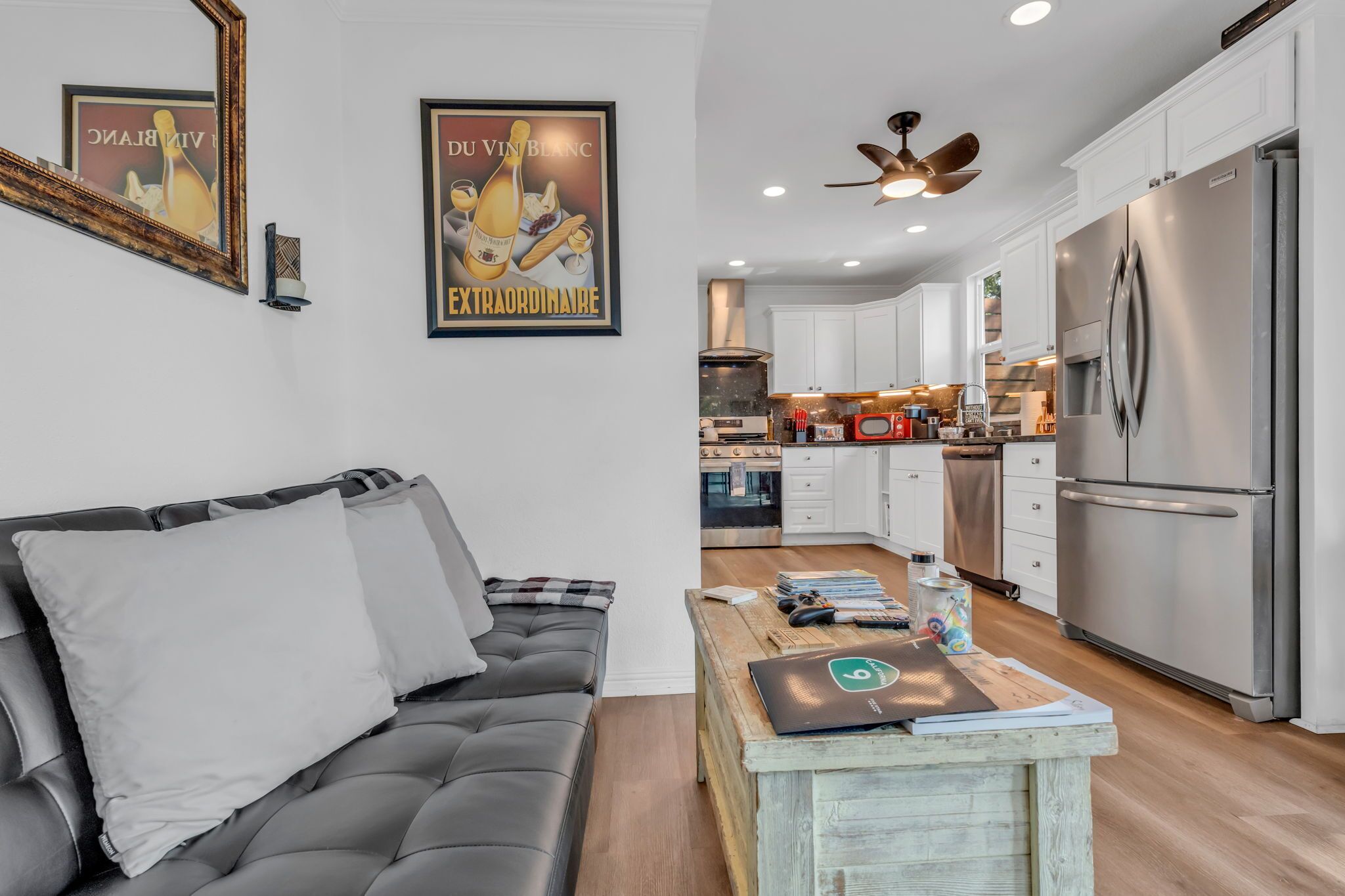 A modern kitchen with white cabinets, a stainless steel refrigerator, and a ceiling fan.