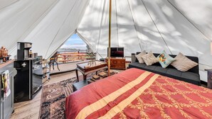 Een tentaccommodatie met een bed, een televisie, een bureau en uitzicht op het landschap.