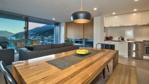 Une cuisine moderne avec une table à manger en bois, un luminaire suspendu noir et une vue sur les montagnes.