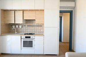A compact kitchen with white cabinets, a built-in oven, a gas stove, and a microwave.